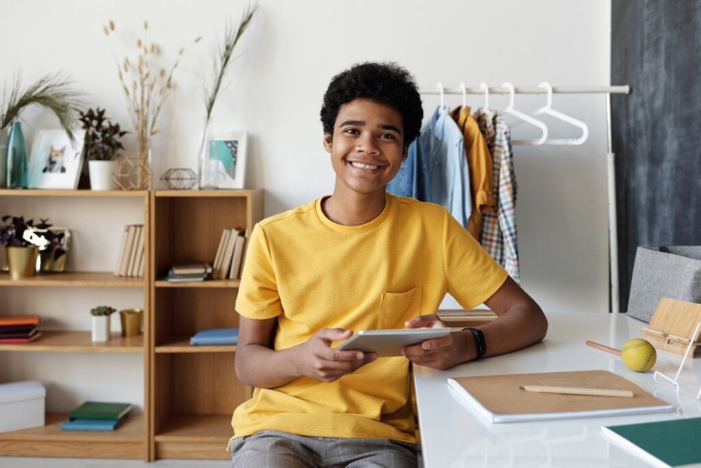 teenage boy sitting and smiling at a desk