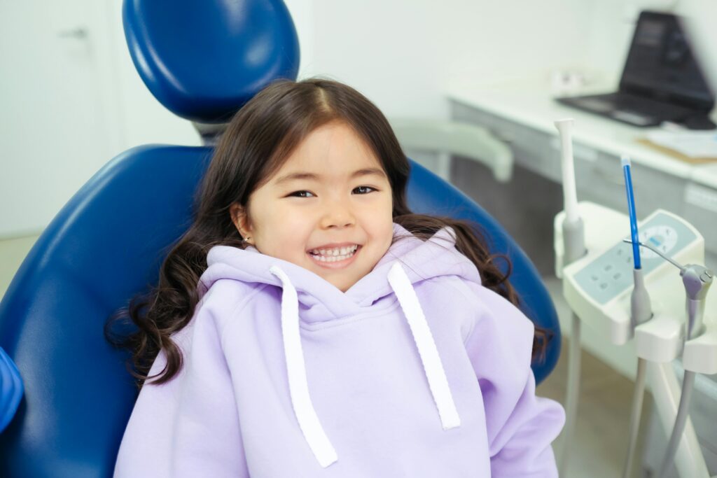 young girl sitting in a dentists chair smiling